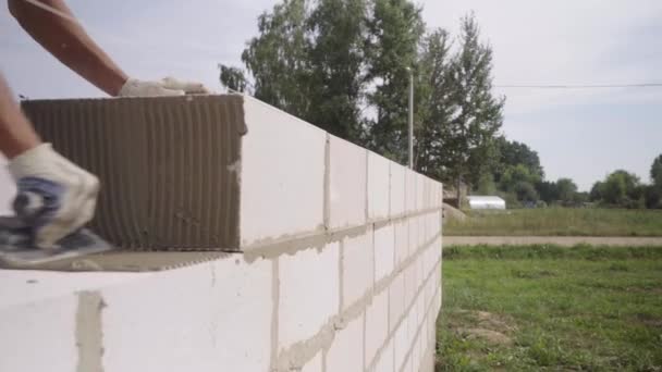한 구획에서 벽을 쌓는 벽돌공, 탁트인 곳에서 퍼티를 위한 화염방사기와 함께. — 비디오
