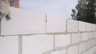 Tuğlacının elleri, beyaz bir bloktan duvar örüyordu..