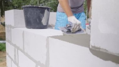 Duvarcı bir blok duvar döşeyen, açık havada macun için bir spatula ile.