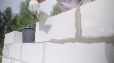İnşaatçı, duvar yapısına spatula ile yapıştırıcı bileşimi veya çözeltisi uygular.