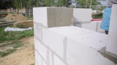 Duvarcı bir blok duvar döşeyen, açık havada macun için bir spatula ile.