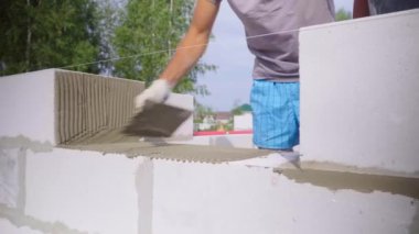 Duvarcı bir blok duvar döşeyen, açık havada macun için bir spatula ile.