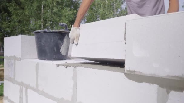 Die Hände eines Maurers legen eine Wand aus einem weißen Block in Großaufnahme. — Stockvideo
