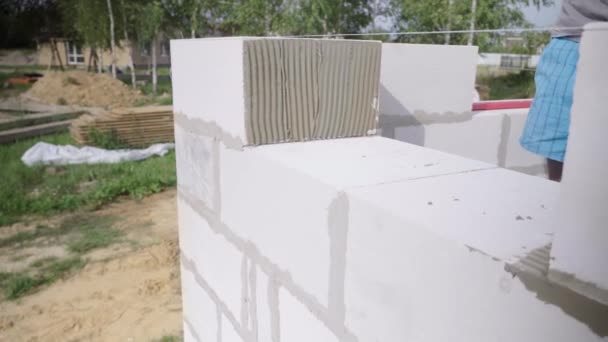 Maurer verlegt Wand aus einem Block, mit Spachtel für Spachtel im Freien. — Stockvideo