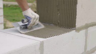 Duvarcı bir blok duvar döşeyen, açık havada macun için bir spatula ile.