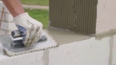 Duvarcı bir blok duvar döşeyen, açık havada macun için bir spatula ile.
