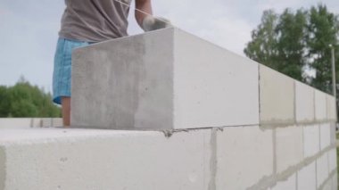 Tuğlacının elleri, beyaz bir bloktan duvar örüyordu..