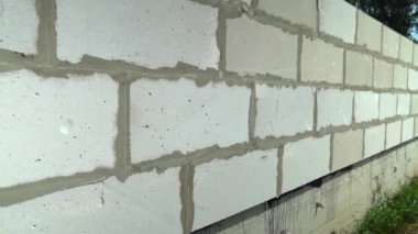 Beyaz blok duvarına yakın plan. Kameranın duvar bloğu boyunca sabit bir şekilde hareket etmesi.