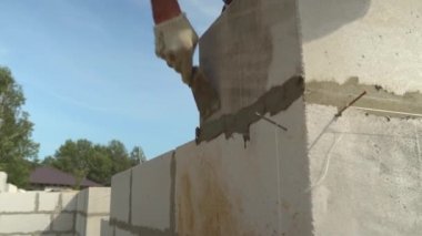 İnşaatçı, duvar yapısına spatula ile yapıştırıcı bileşimi veya çözeltisi uygular.