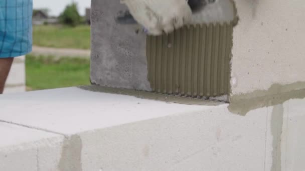 건축자는 다음 블록을 넣기 위해 스파 툴라를 이용하여 접착제 구성이나 용액을 적용 한다. — 비디오