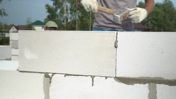 As mãos de um pedreiro põem uma parede de um bloco branco close-up. — Vídeo de Stock