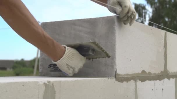 Maurer verlegt Wand aus einem Block, mit Spachtel für Spachtel im Freien. — Stockvideo