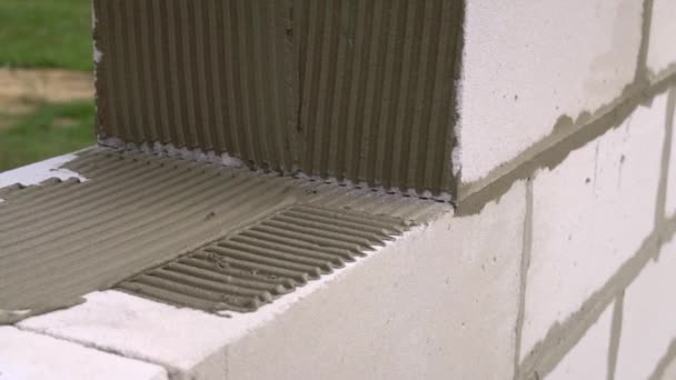 Murtegelvägg från ett block, med spatel för spackel utomhus. — Stockvideo