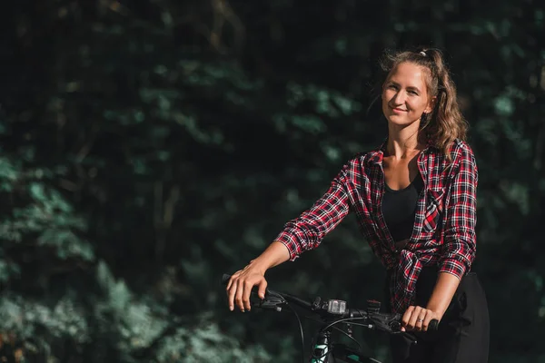 격자무늬 셔츠를 책가방을 공원에 자전거를 여자의 복제물 — 스톡 사진