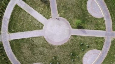 Bisikletli bir kadının şehir parkındaki yuvarlak bir yolda bisiklet sürüşünün en iyi görüntüsü..
