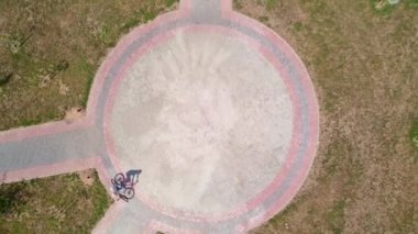 Bisikletli bir kadının şehir parkındaki yuvarlak bir yolda bisiklet sürüşünün en iyi görüntüsü..