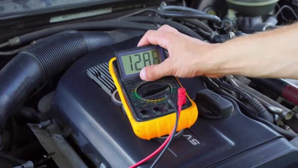 Spanning van de startaccu van de auto wordt gemeten door multimeter. spanning 13 volt, — Stockvideo