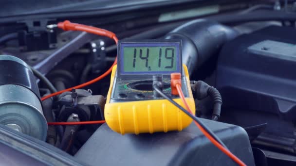 Arabanın aküsünün voltajı çoklu metre ile ölçülür. voltaj 14 volt, — Stok video