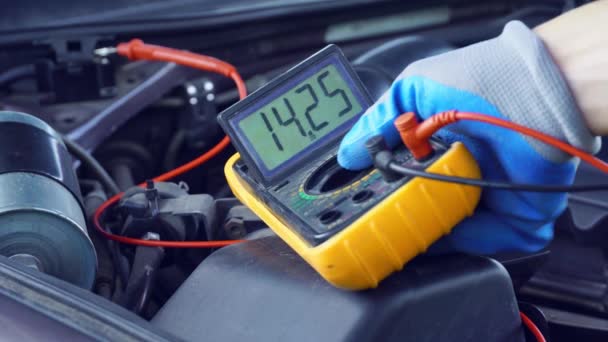 Voltaje de la batería de arranque del coche se mide por multímetro. voltaje 14 voltios, — Vídeo de stock