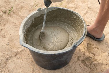 Kovada çimento harcı ile elektrikli inşaat matkabını birbirine karıştırmak.