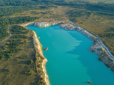 Krichev yakınlarındaki Belarus 'ta yapay bir tebeşir ocağı gölü görüntüsü. Turkuaz su, yaz mevsiminde, açık bir çukurda. Tebeşirin çıkarılması sırasında insan yapımı dağlar oluştu..