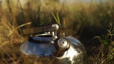 Kadınların elleri plastik bir şişeden metal bir çaydanlığa su döker.