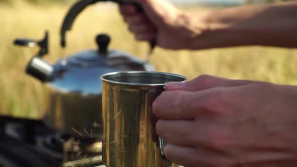 Жіночі руки вливають воду в залізний кухоль з чайника. в природі , — стокове відео