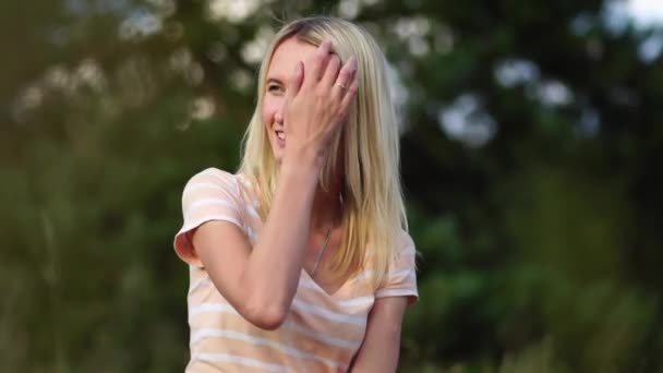 Primo piano di una ragazza sorridente che guarda la telecamera seduta nella natura in un campo. — Video Stock