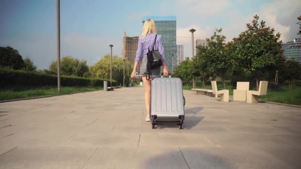 Вид сзади на путешественницу, она идет через южный город — стоковое видео