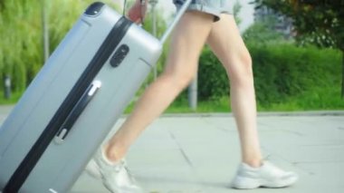 Kadınların ayakları kaldırımda yürür ve arkalarında bir bavul taşır..