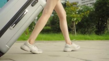 Kadınların ayakları kaldırımda yürür ve arkalarında bir bavul taşır..