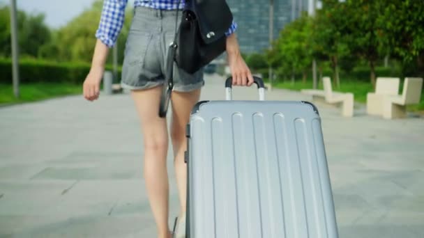 Les pieds des femmes marchent sur le trottoir et portent une valise derrière eux. — Video