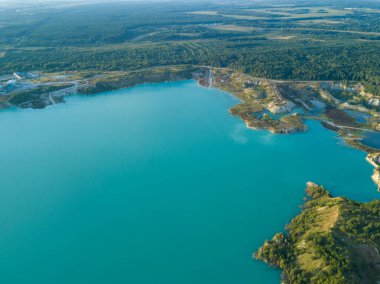 Krichev yakınlarındaki Belarus 'ta yapay bir tebeşir ocağı gölü görüntüsü. Turkuaz su, yaz mevsiminde, açık bir çukurda. Tebeşirin çıkarılması sırasında insan yapımı dağlar oluştu..