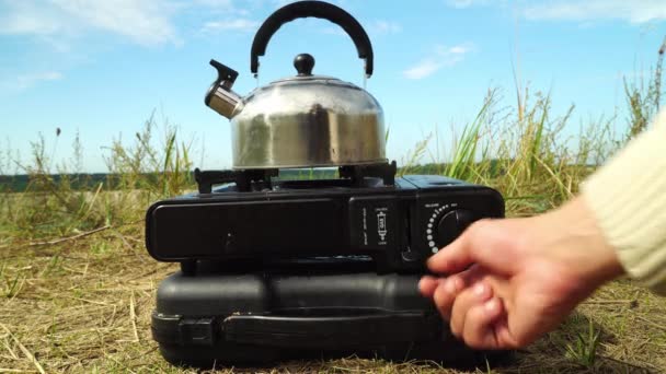Female hands, close-up, put a kettle on a gas burner for heating water in nature — Stock Video