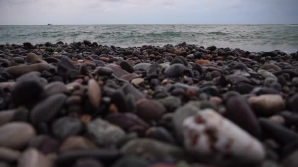 Akşamları taştan bir sahile yakın çekim. Gün batımında deniz. — Stok video