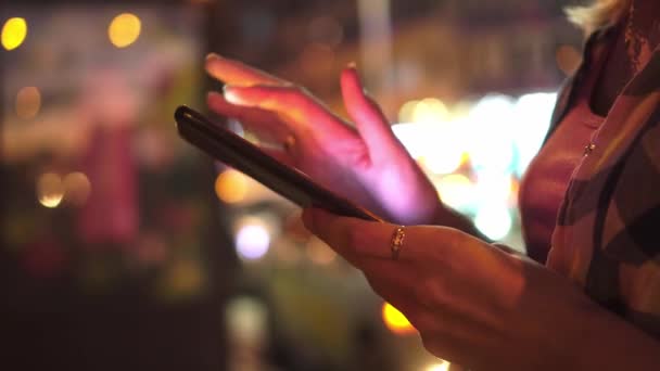 Focus op de hand van de vrouw met behulp van smartphone, nacht stad straat vol neon licht. — Stockvideo