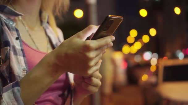 Focus op de hand van de vrouw met behulp van smartphone, nacht stad straat vol neon licht. — Stockvideo