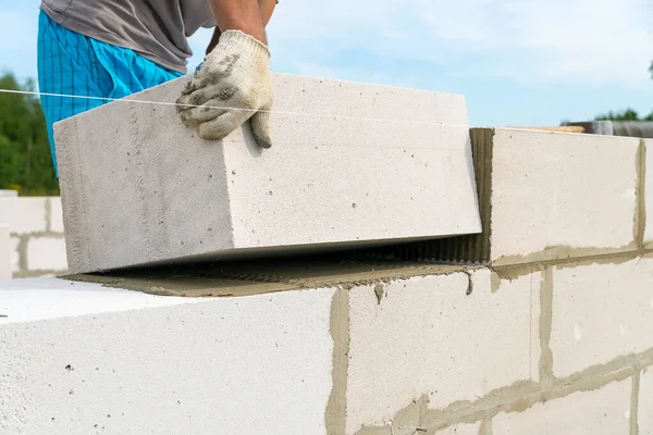 İnşaatçı, bir evin inşaat sahasında beton bloklardan bir duvar yapıyor. Bir ev inşa etme kavramı