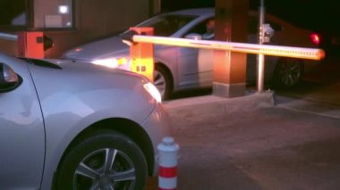 Otomatik otoyol otoparkın önünde. Bariyer açılır, araba geçer.