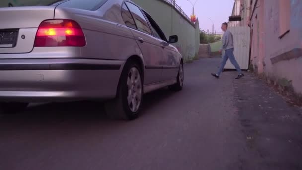 Κοντινό πλάνο ενός αυτοκινήτου BMW που κινείται κατά μήκος ενός εγκαταλελειμμένου δρόμου — Αρχείο Βίντεο