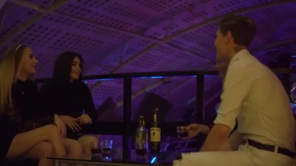 Guys and girls relax at a table in a nightclub. They laugh, drink, talk . — Stock Video