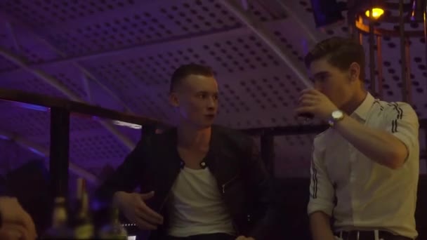 Jungs und Mädchen entspannen sich an einem Tisch in einem Nachtclub. Sie lachen, trinken, reden . — Stockvideo