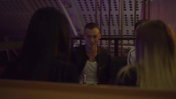 Guys and girls relax at a table in a nightclub. They laugh, drink, talk . — Stock Video