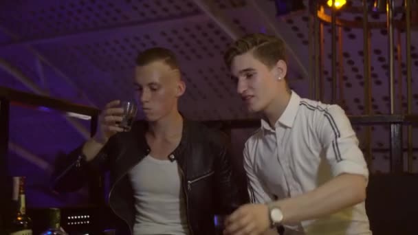 Ragazzi e ragazze si rilassano a un tavolo in un nightclub. Ridono, bevono, parlano . — Video Stock