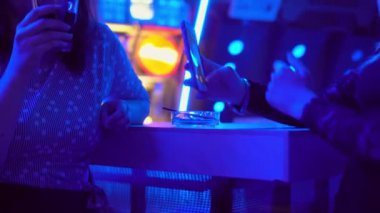 Barın arkasındaki gece kulübünde iki kadının yakın çekimi. Cam ve akıllı telefon..