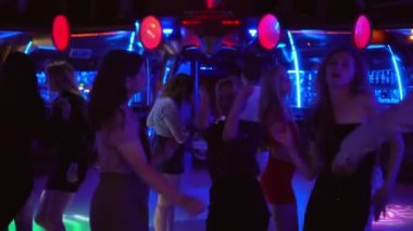 Bir grup genç gece kulübünde dans ediyor, eğleniyor ve gülüyorlar.