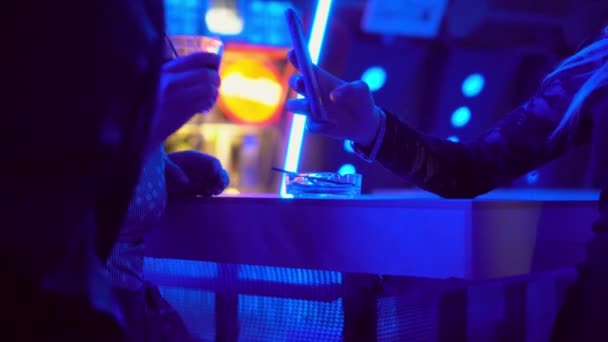 Primo piano di mani di due donne in nightclub dietro bar. vetro e smartphone. — Video Stock