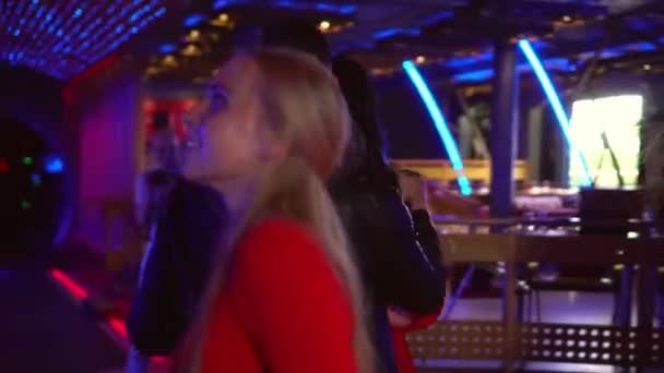Красивый улыбающийся молодой человек и женщина танцуют в клубе среди других людей — стоковое видео