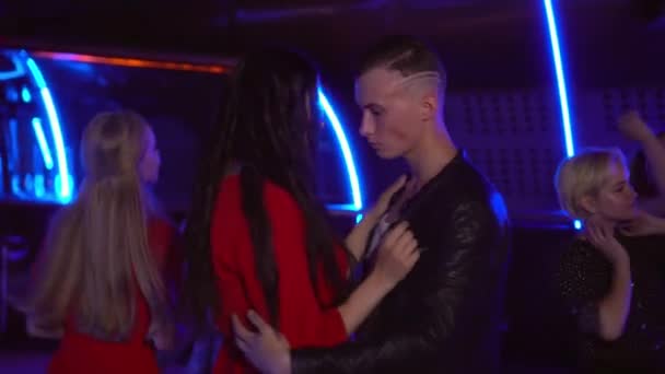 Mooie jongeman en een vrouw dansen onder andere in een club. — Stockvideo
