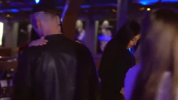 Krásný mladý muž a žena tančí v klubu mezi ostatními lidmi. — Stock video